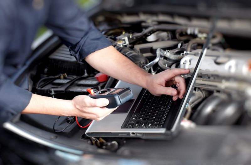 Kfz-Mechatroniker führt Fehlerdiagnose mithilfe eines Laptops durch